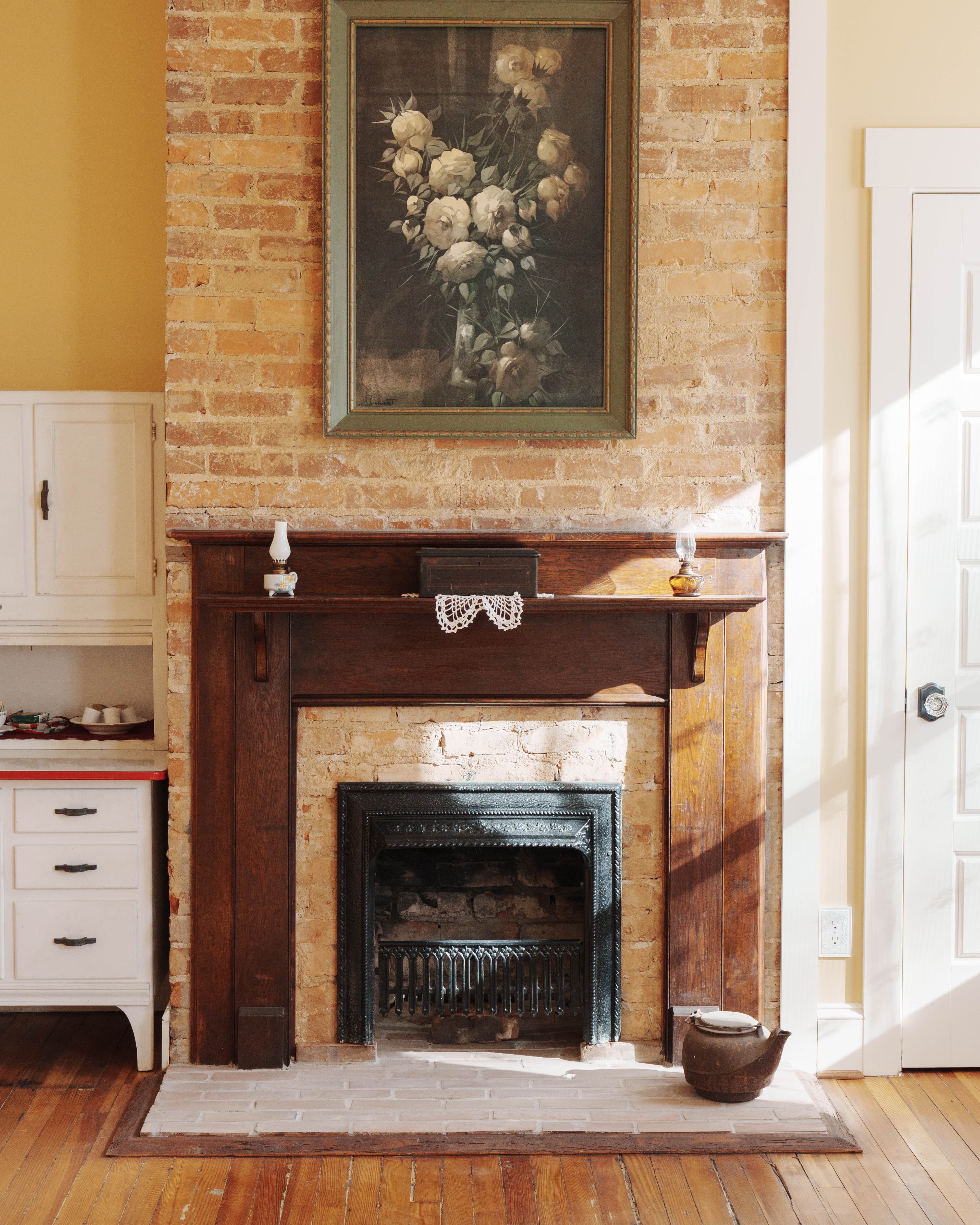 A brick fireplace with a dark wooden mantel and a framed painting above.