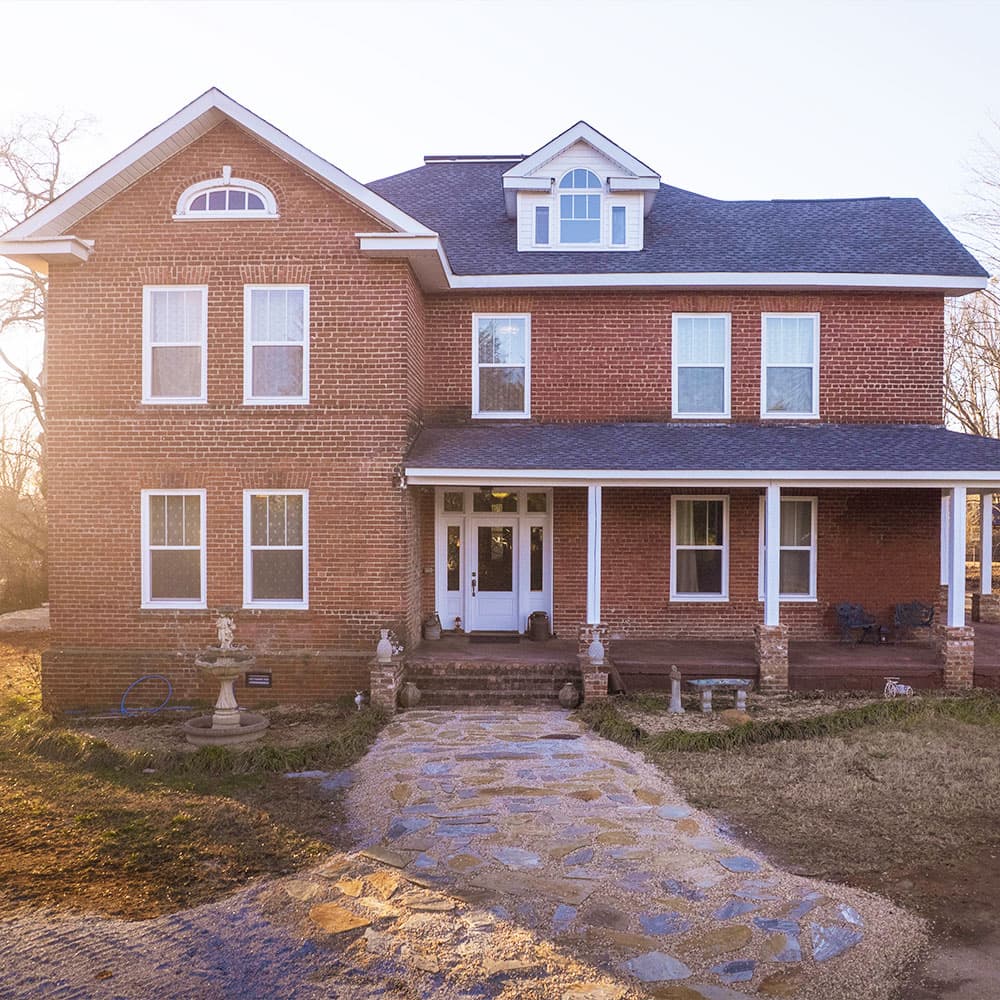 A large two-story red brick house with a stone pathway and front porch.