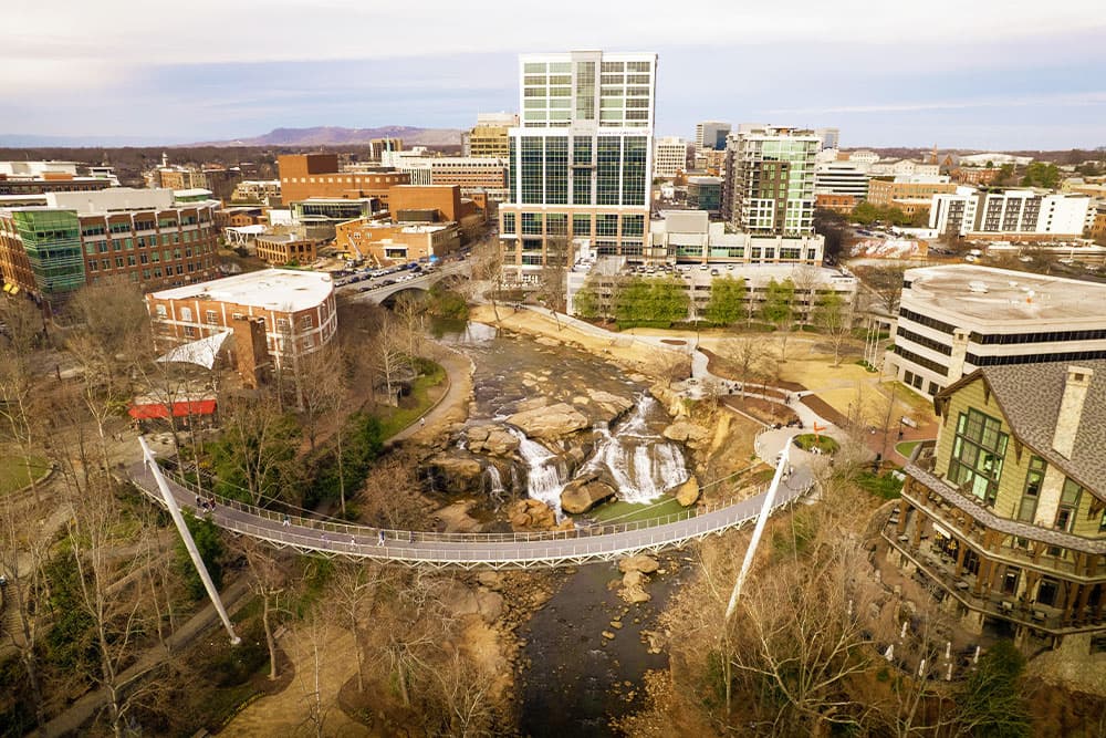 Aerial view of a cityscape featuring a bridge over a stream and a waterfall.