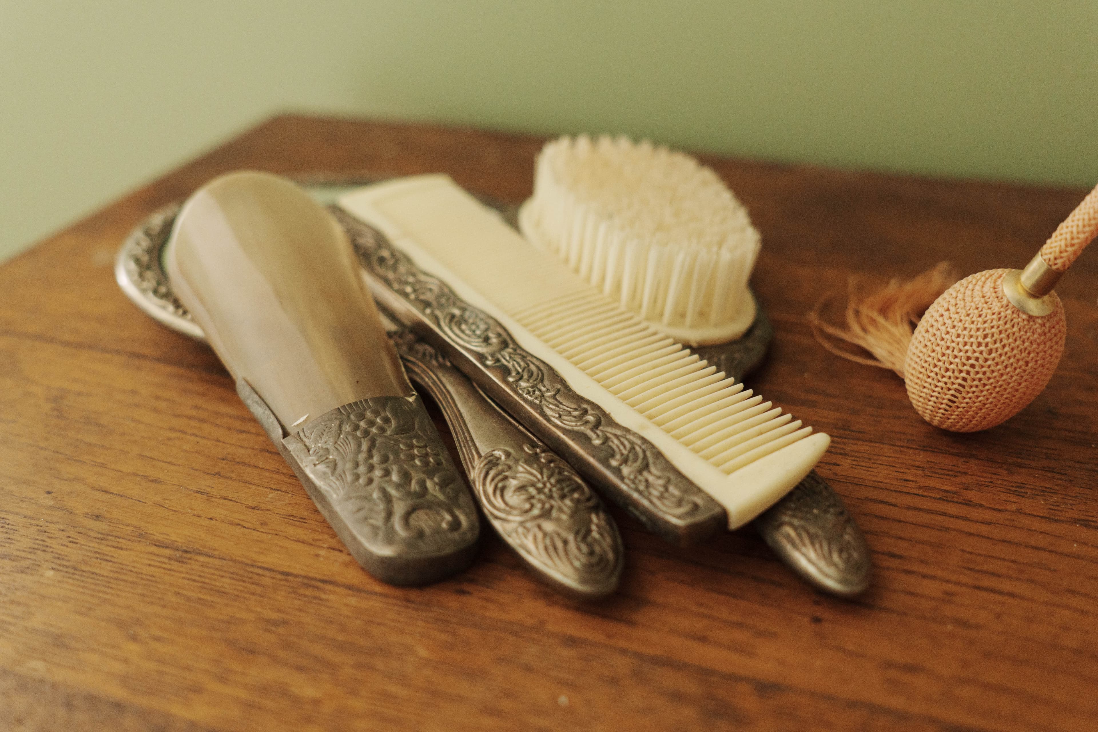 A collection of vintage grooming tools, including a brush, comb, and mirror, arranged on a wooden surface.